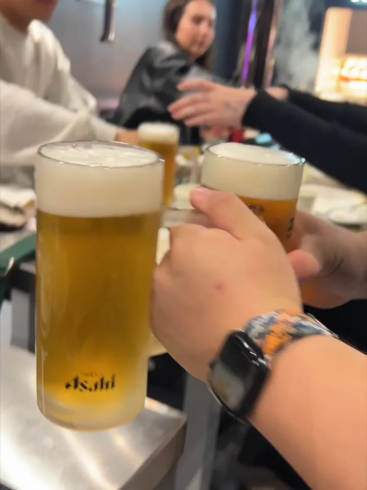 Friends clinking beer glasses over a Korean BBQ table at GOGI